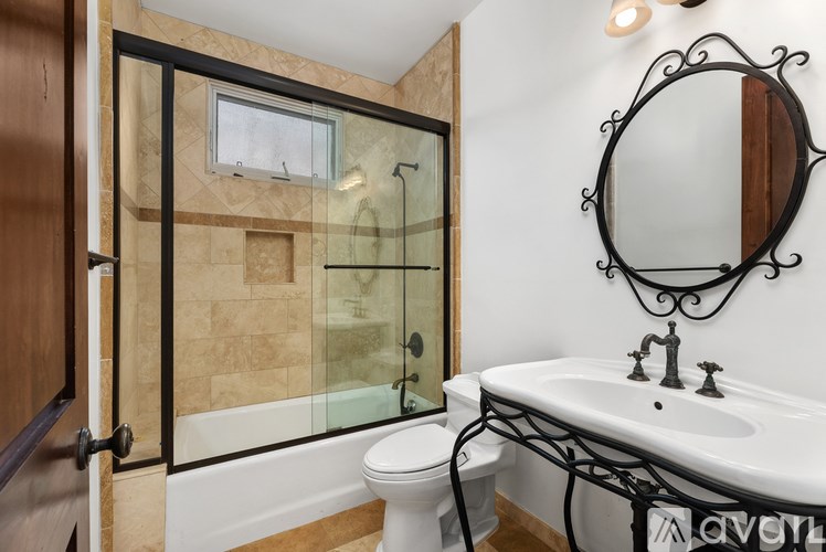 A bathroom with a white sink, toilet, and a glass shower stall.