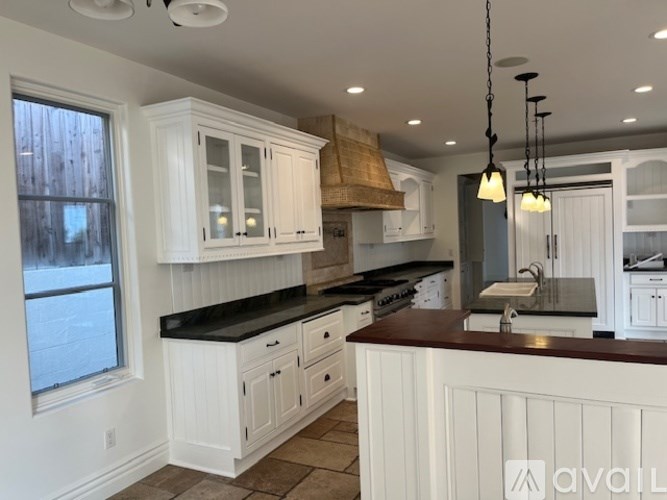 A kitchen with white cabinets and a black countertop.