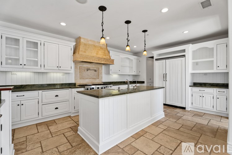 A modern kitchen with granite countertops and pendant lights.