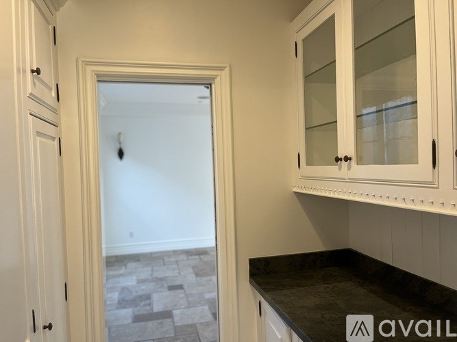 A kitchen with white cabinets and a black countertop.