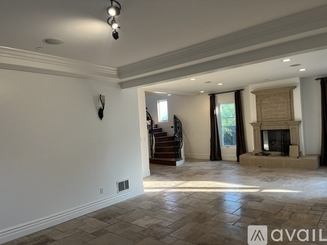 A spacious living room with a fireplace and a staircase leading to another room.