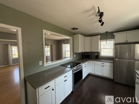 A kitchen with white cabinets and a stainless steel refrigerator.