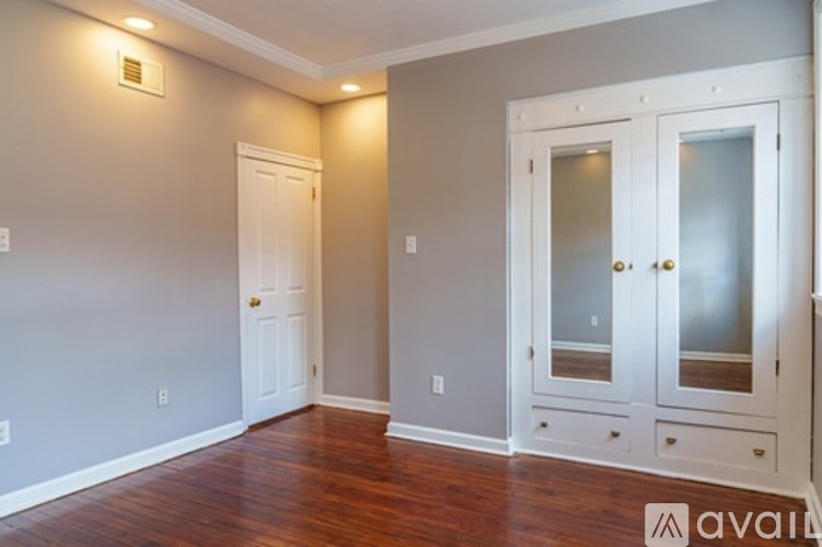 A room with a white door and a wooden floor.