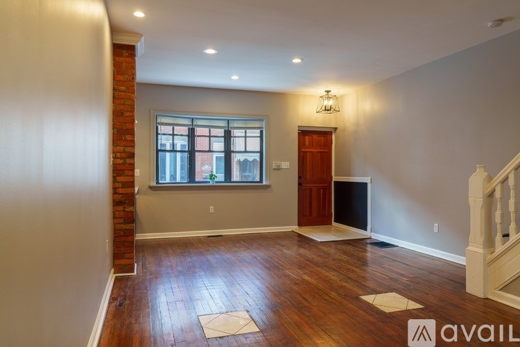A room with a wooden floor and a brick column.