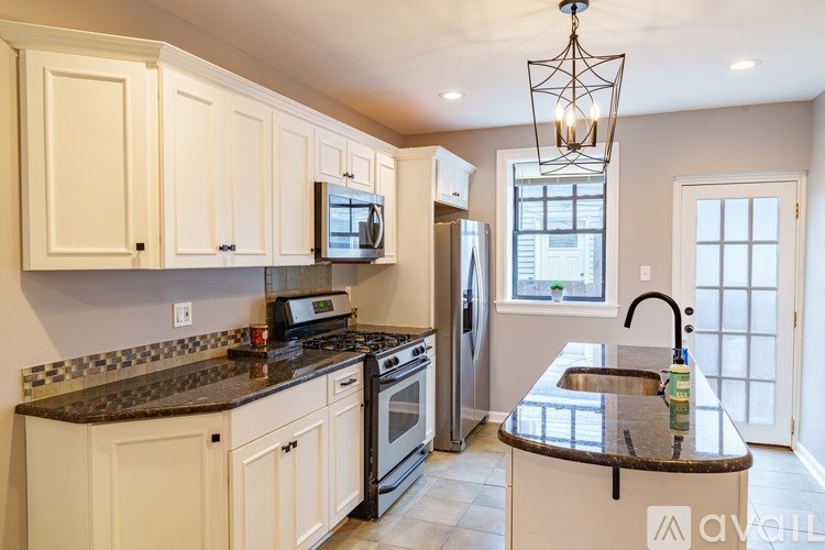 A kitchen with white cabinets and a black countertop.