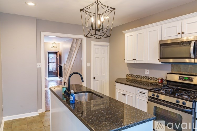 A kitchen with a black granite countertop and white cabinets.