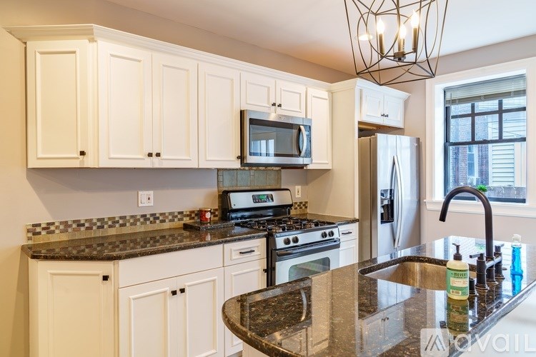 A kitchen with white cabinets and a granite countertop.