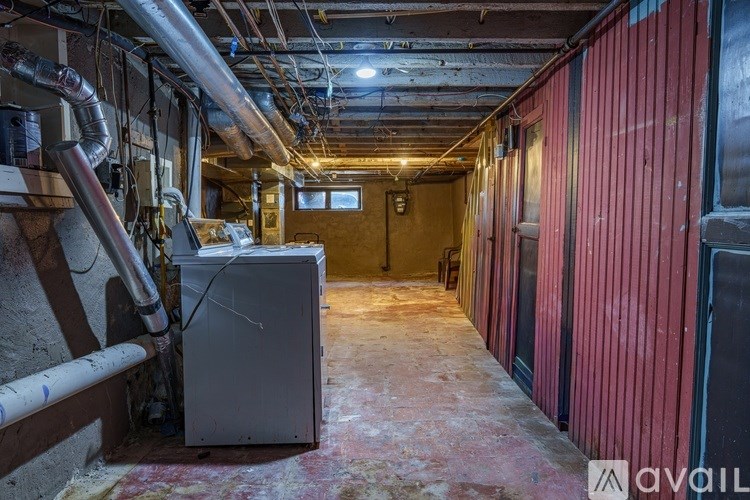 A dirty, unfinished basement with a furnace and pipes.