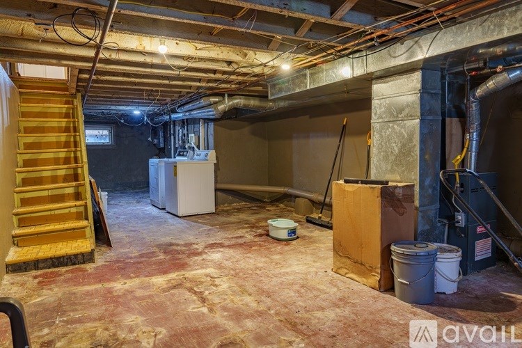 A room with a carpeted floor and a staircase on the left side.