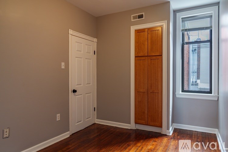 A room with a white door and wooden cabinet.