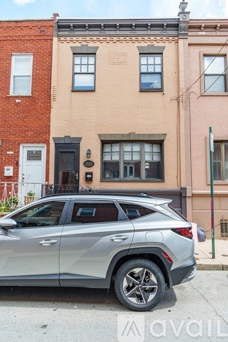 A silver SUV is parked in front of a two-story building.