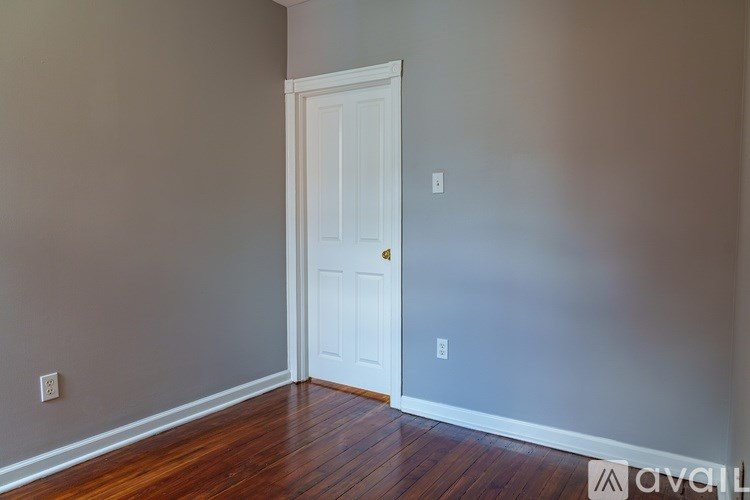 A room with a white door and wooden floor.