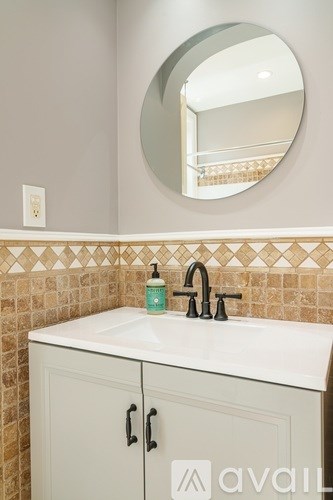 A bathroom with a white sink and a round mirror.