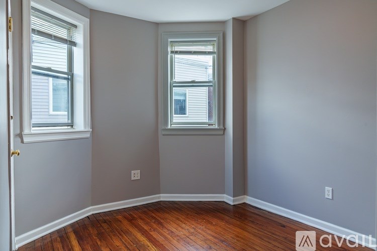 A room with two windows and wooden floors.