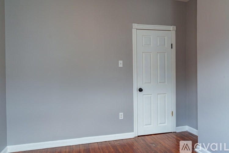 A white door is in a room with a wooden floor.