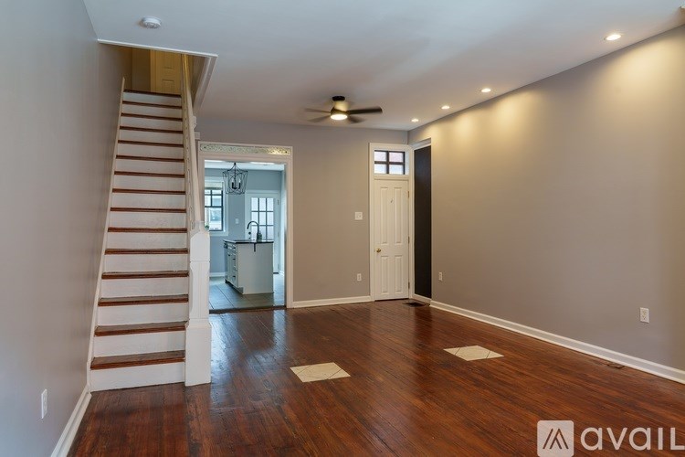 A spacious room with wooden floors and a staircase leading to the upper level.