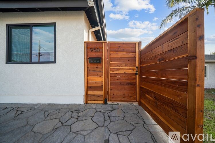 A wooden gate with the number 950 on it is open.