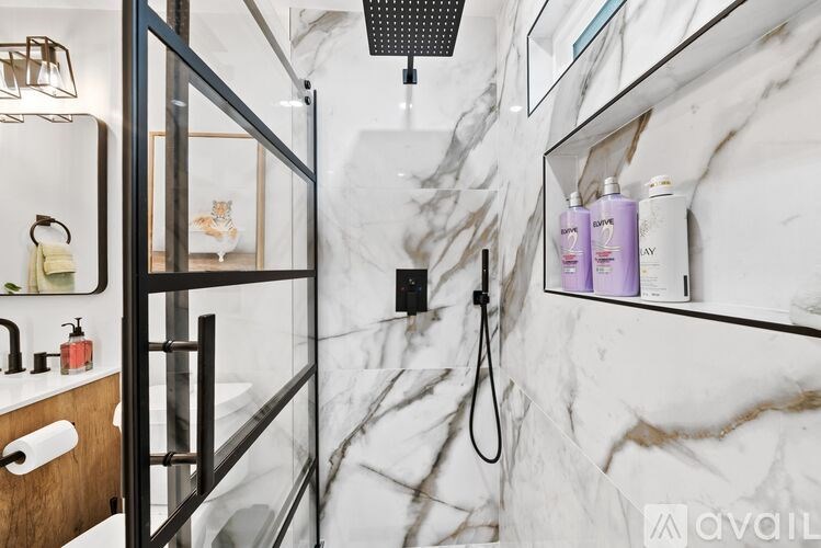 A bathroom with marble walls and a glass shower stall.