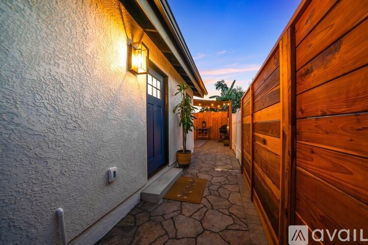 A narrow alley with a white wall on the left and a wooden fence on the right.