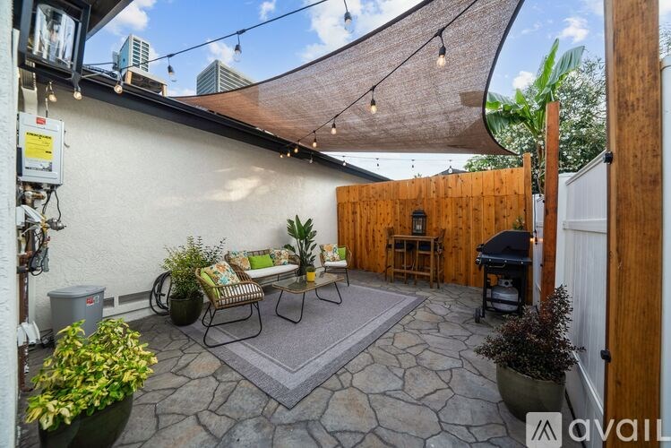 A patio with a table and chairs under a shade sail.