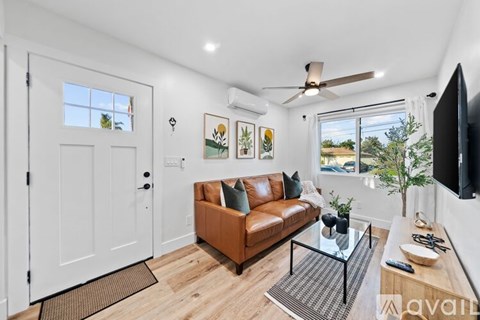 A living room with a brown couch and a flat screen TV mounted on the wall.