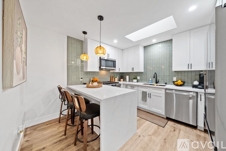 A modern kitchen with a white island and stainless steel appliances.
