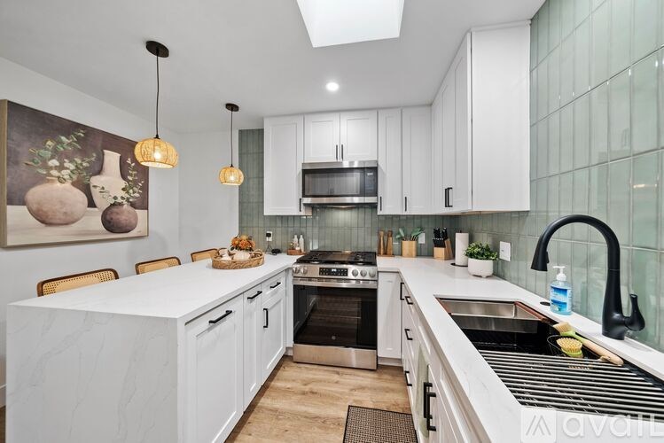 A modern kitchen with white cabinets and a marble countertop.