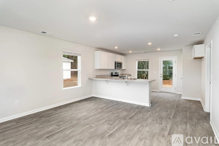 A spacious living room with a kitchen area in the background.