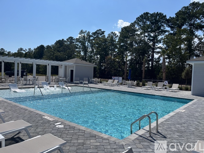 A pool with a few chairs and a building in the background.