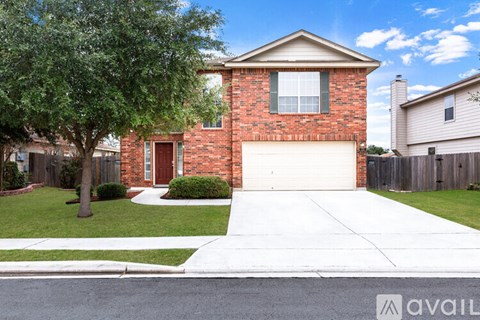 A red brick house with a white garage door and a tree in front.