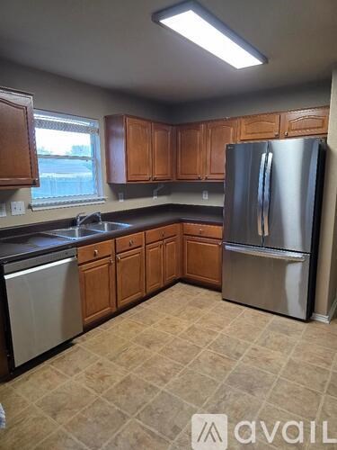 A kitchen with wooden cabinets and a stainless steel refrigerator.