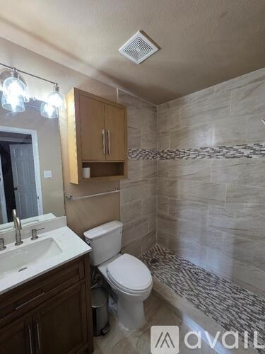 A bathroom with a toilet, sink, and a mirror.