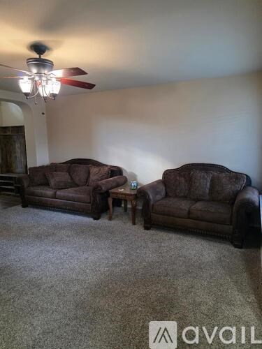 A living room with two couches and a ceiling fan.