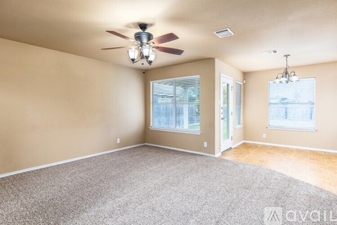 A spacious room with a ceiling fan and carpeted floor.