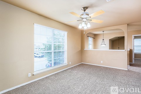A spacious room with a ceiling fan and a window with blinds.