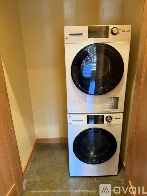 A white front loading washing machine with a black door is in a room.
