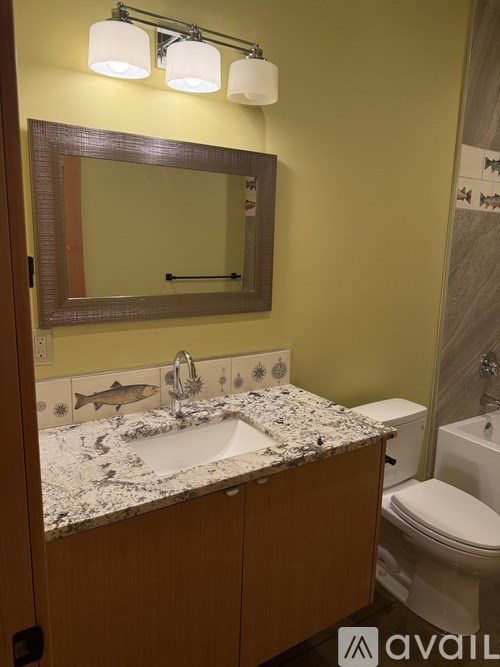 A bathroom with a marble counter top and a mirror above it.