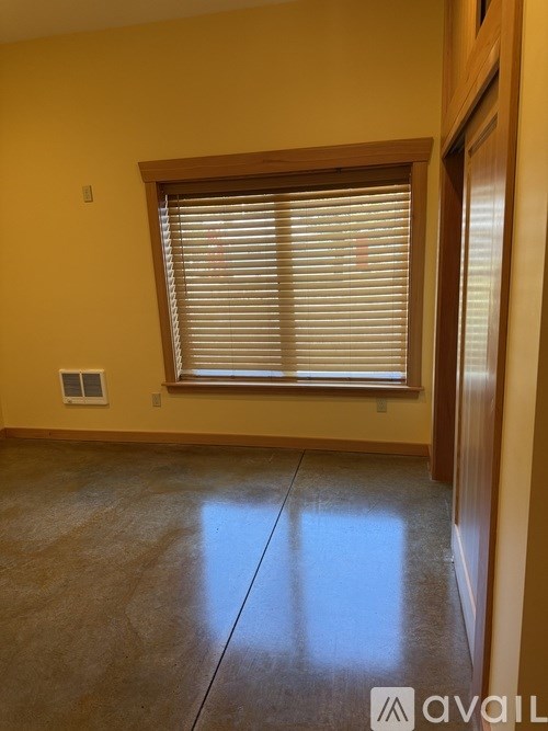 A room with a window covered by white blinds.