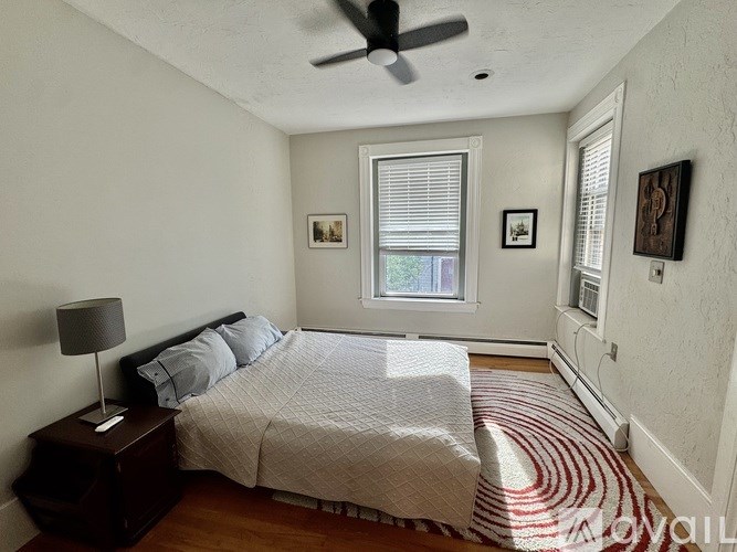 A bedroom with a bed, nightstand, and pictures on the wall.