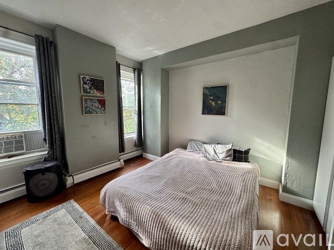 A bedroom with a bed, a speaker, and a window with curtains.