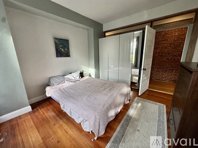 A bedroom with a bed, a rug, and a painting on the wall.