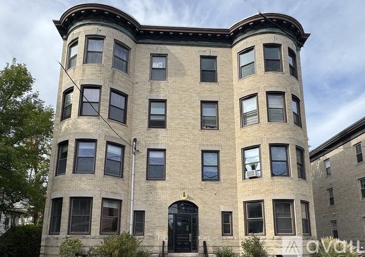 A large, two-story building with a curved corner and a black door.