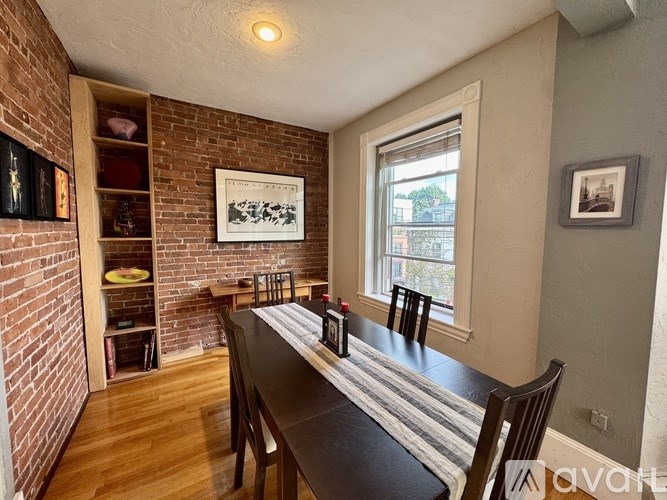 A dining room with a brick wall and a wooden table.
