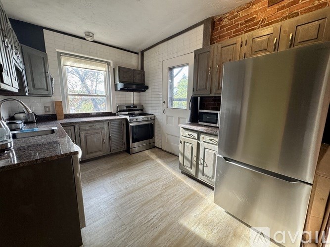 A kitchen with a stainless steel refrigerator and wooden cabinets.