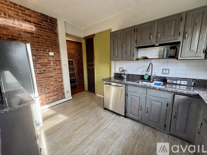 A kitchen with a brick wall and wooden flooring.