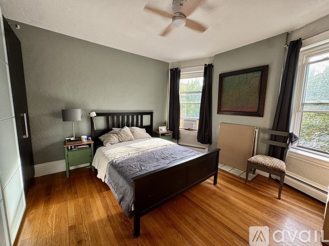 A bedroom with a bed, nightstand, chair, and window.