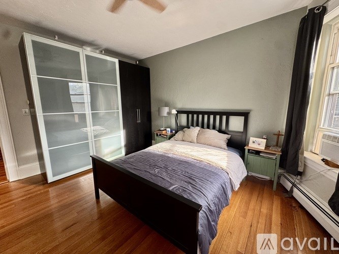 A bedroom with a bed, nightstand, and a glass door cabinet.
