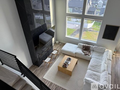 A living room with a white couch and a coffee table in front of a large window.