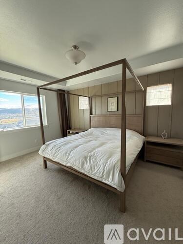 A bedroom with a four-poster bed and a window overlooking the city.