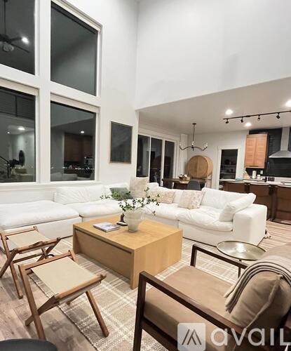 A living room with a white couch, wooden coffee table, and a large window.